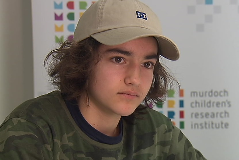 Riley Collins sits at a table wearing a cap.