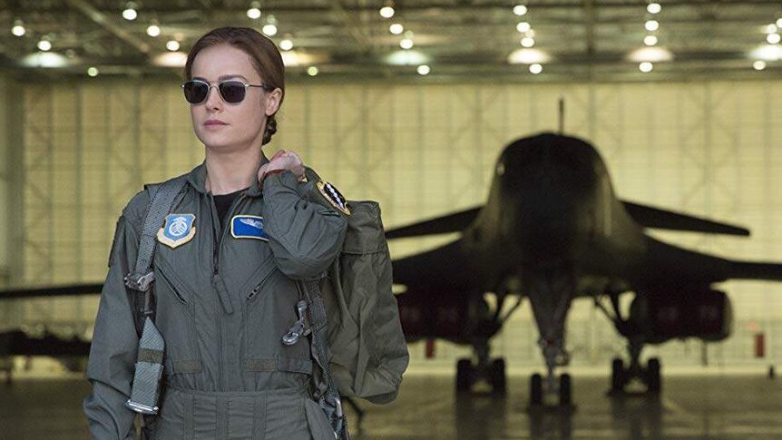 Carol Danvers exits a hanger wearing her air force uniform.