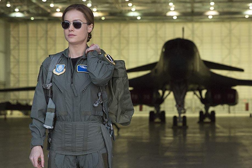 Carol Danvers exits a hanger wearing her air force uniform.