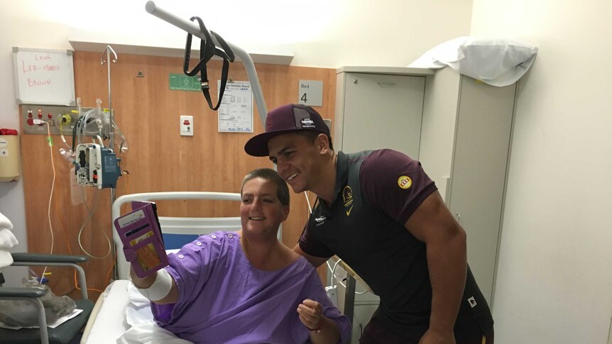 Broncos player Kodi Nikorima poses for a selfie with a woman in a hospital bed.