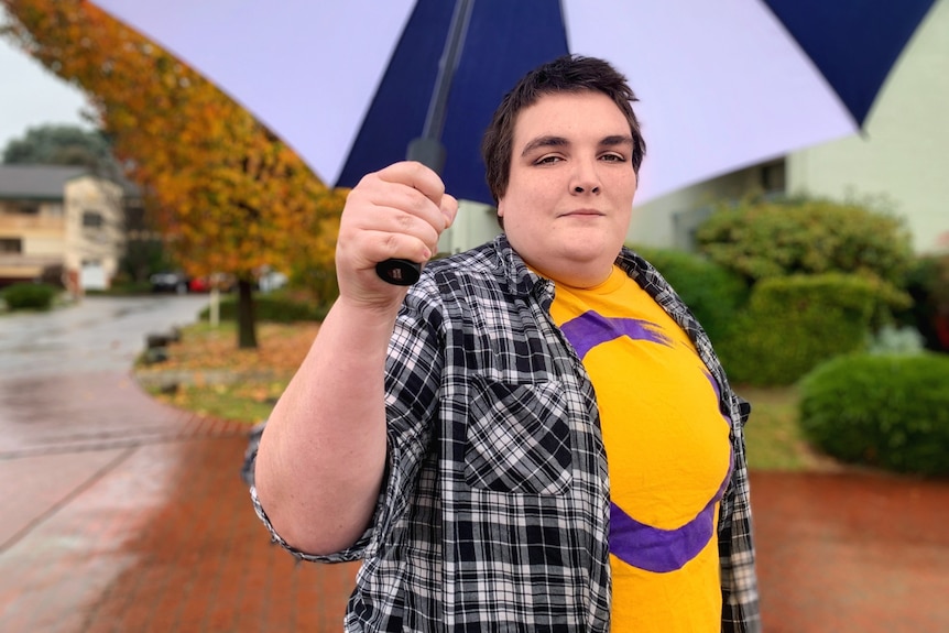 Person wearing a yellow shirt holding an umbrella. 