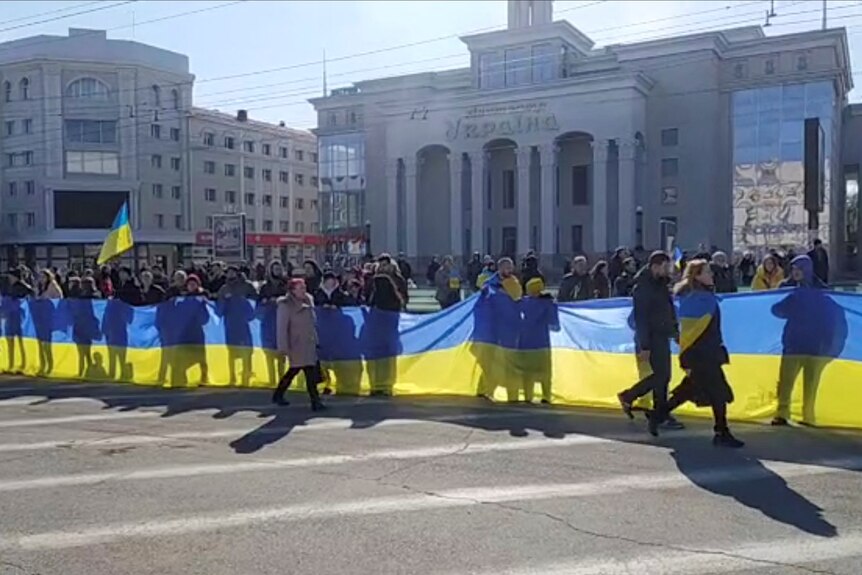 People hold a banner in the colours of the Ukrainian flag 