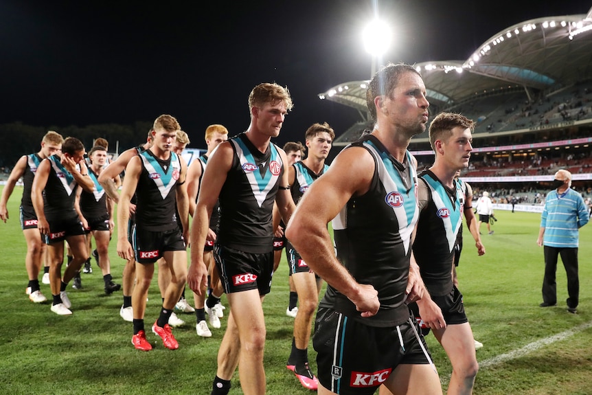 Sad looking Port Adelaide players walk off the field with their heads down