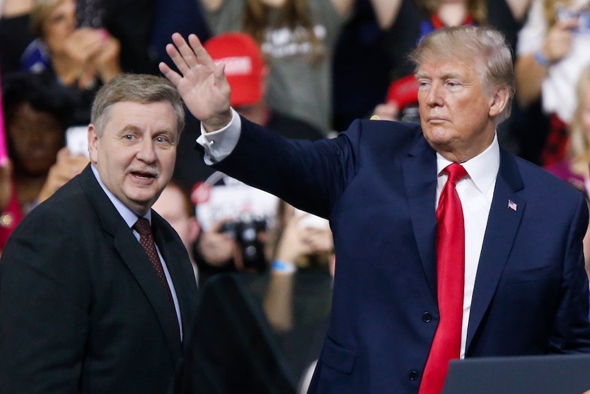 Rick Saccone stands next to Donald Trump, who is waving to supporters.