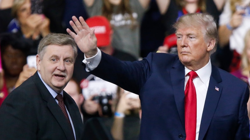 Rick Saccone stands next to Donald Trump, who is waving to supporters.