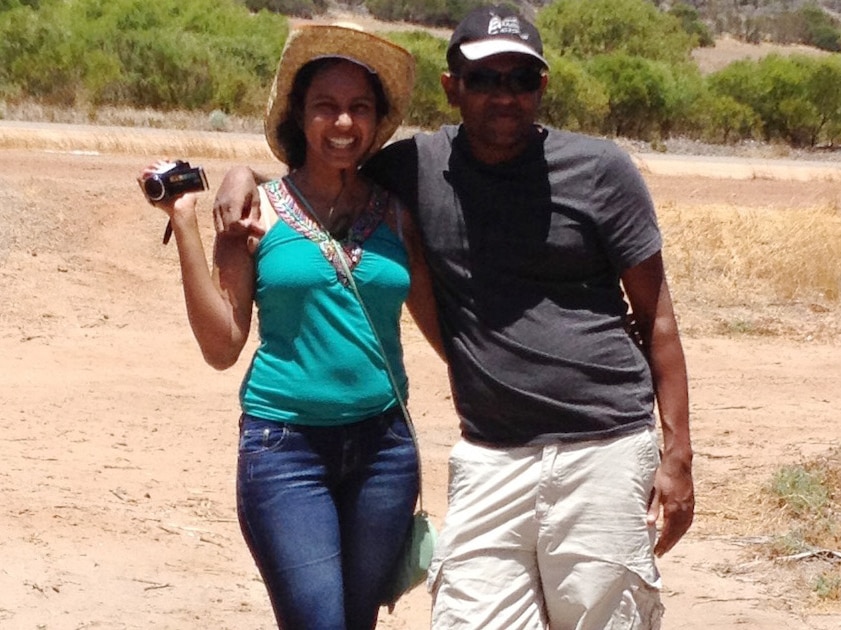 Chamari Liyanage stands on the side of the road holding a camera next to her husband and fellow doctor, Dinendra Athukorala.