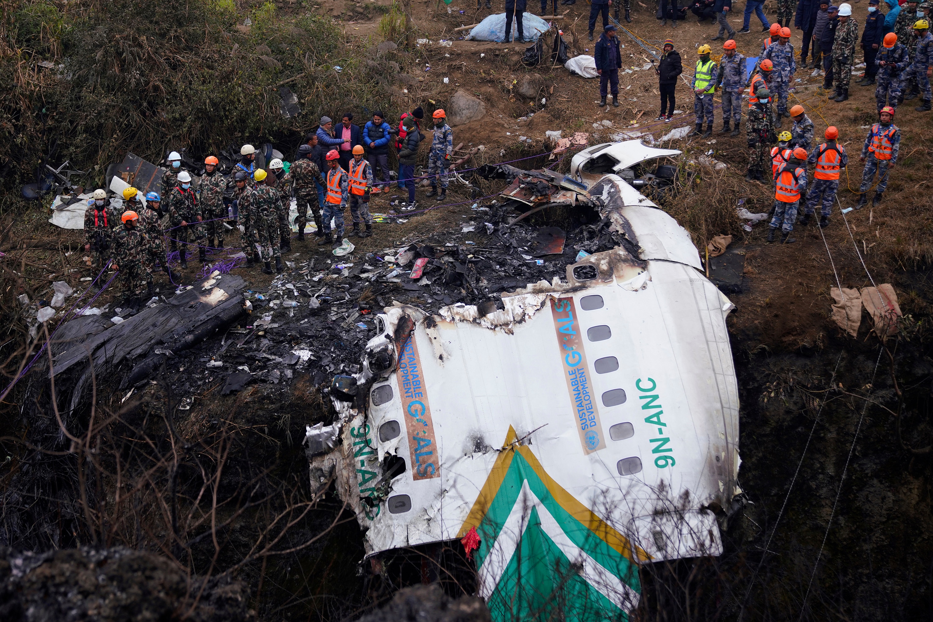 People surround plane wreckage. 