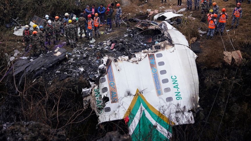 People surround plane wreckage. 