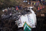 People surround plane wreckage. 