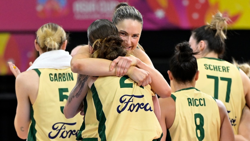 A smiling Australian Opals basketballer hugs a teammates as they celebrate a win. 