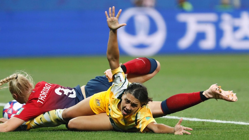 Australia's Sam Kerr is on her stomach on the ground, with Thorisdottir still on top of her, her arms raised in protest