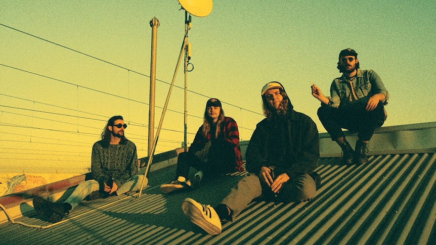 Photograph of the members of Dear Seattle sitting on top of a house roof.