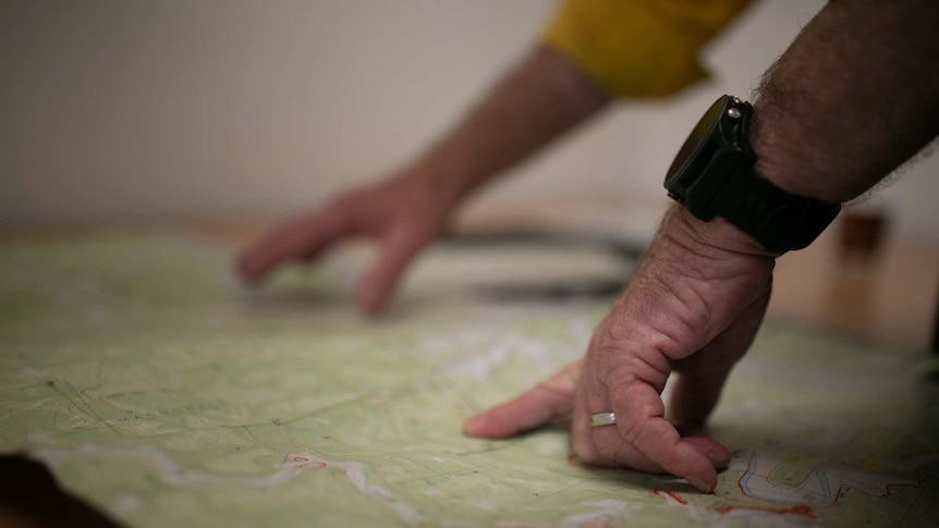 Two hands pointing at a map on a table