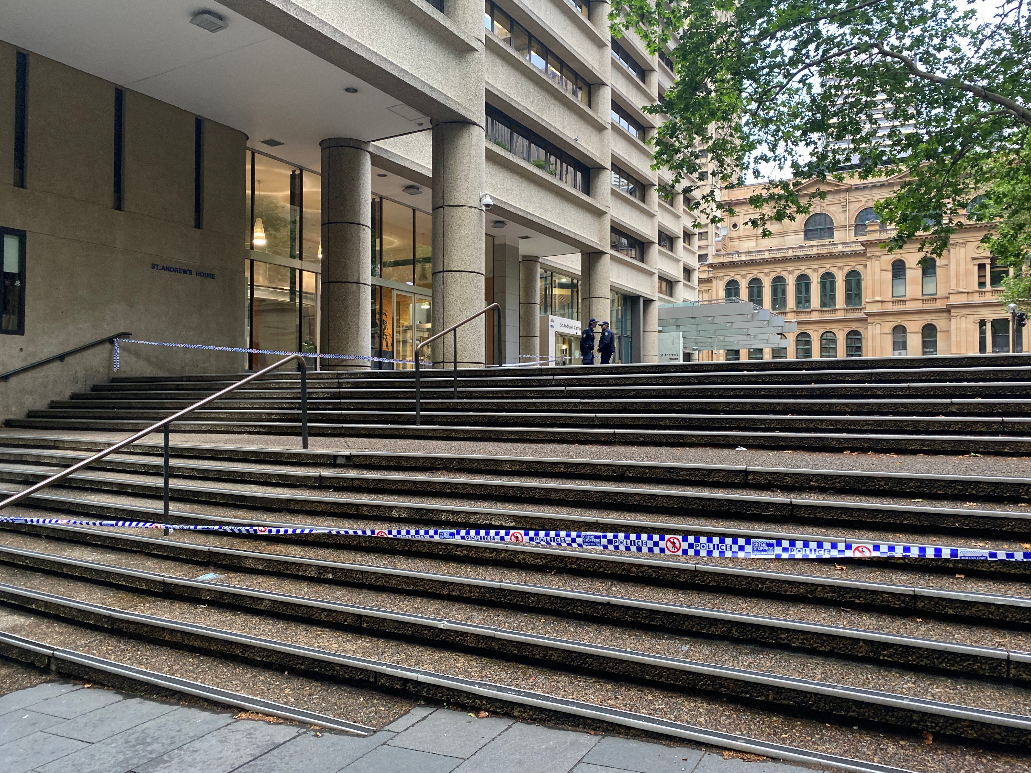 Police crime scene tape stretches across a set of stone steps outside St Andrew's Cathedral School in Sydney CBD