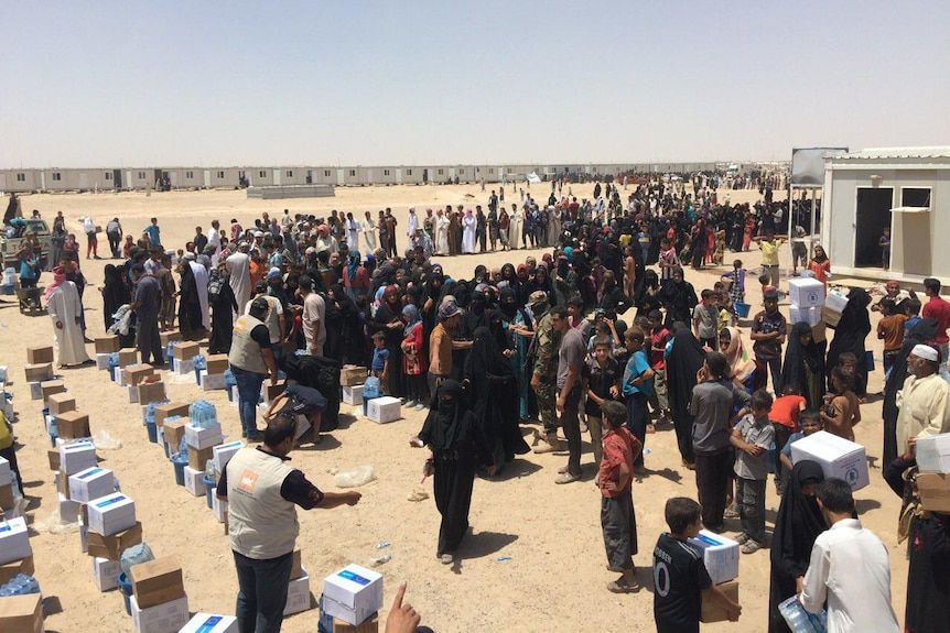 Iraqis wait in line for relief supplies at a displacement camp