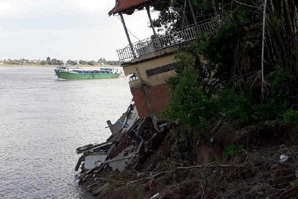 A house slanted toward the river after the river bank has eroded.