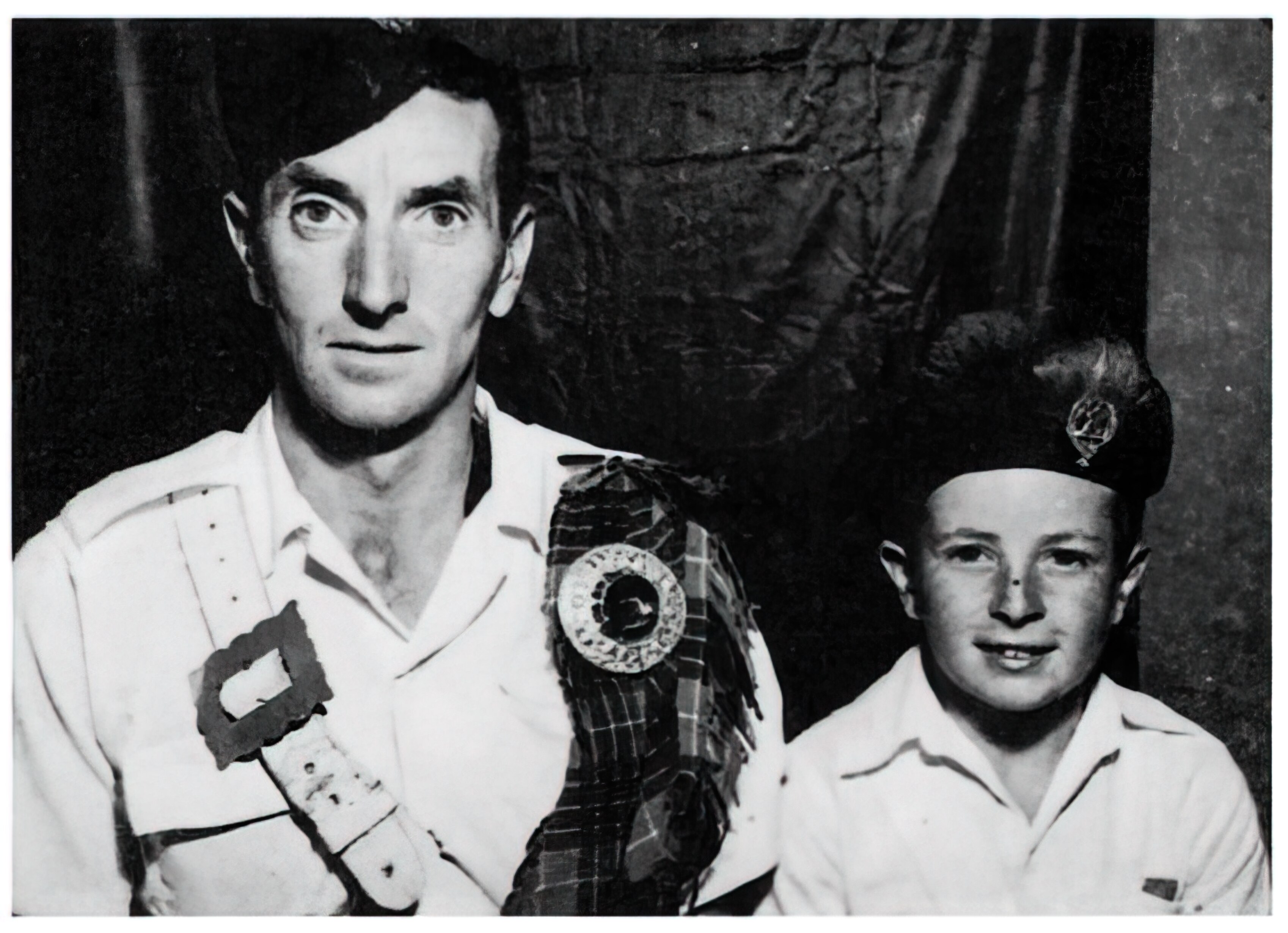 A young Bon Scott (of AC/DC fame) with his father, Charles Belford Scott, both wearing Scottish pipe band uniforms.