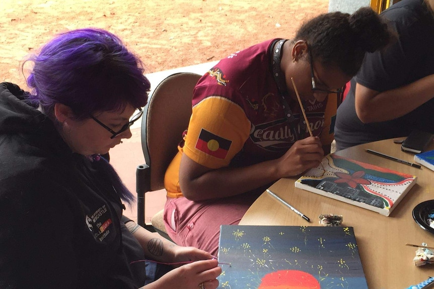 Karlie painting a story told to her by an elder about spiderwebs connecting the universe.