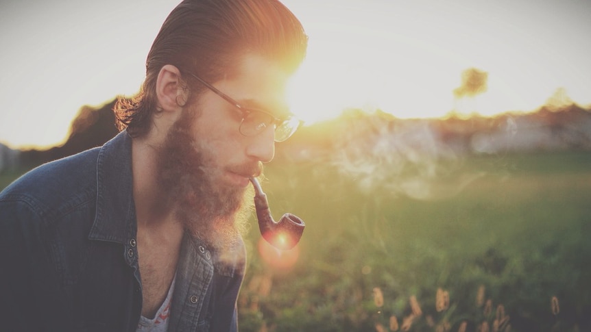 Hipster man smoking a pipe in gorgeous afternoon light.
