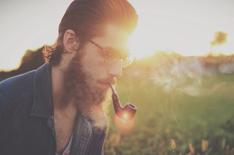 Hipster man smoking a pipe in gorgeous afternoon light.