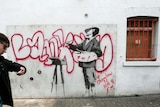 A man walks past a graffiti mural by British artist Banksy