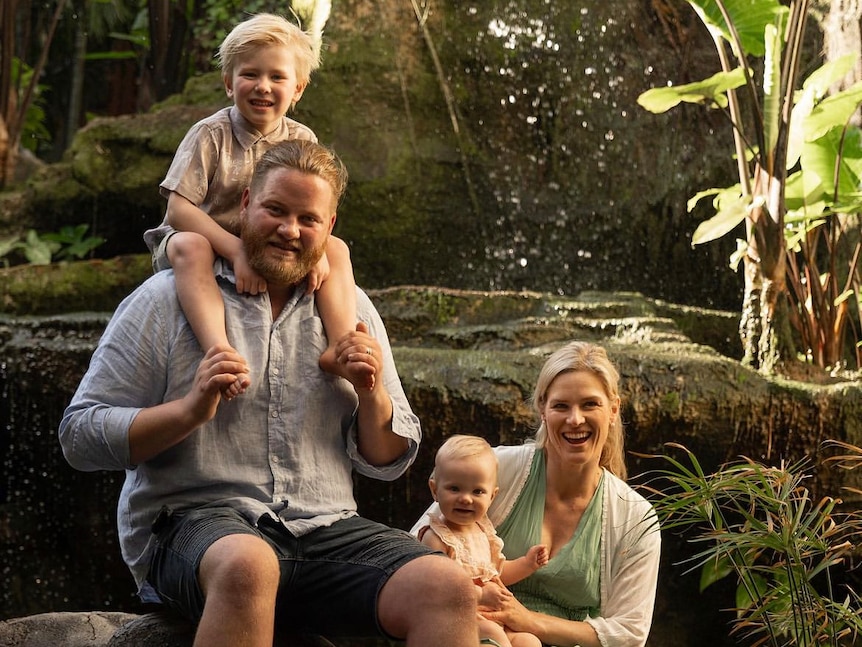 A family portrait of the Næss family, with natural rocks and waterfall in background.