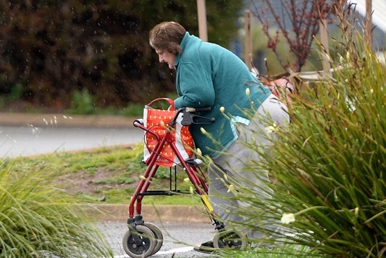 Vicki Brown walks with her walking frame in the rain.