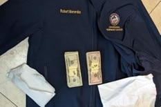 Two piles of cash are placed on top of a black jacket that says Robert Menendez.
