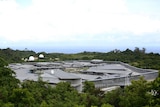 A wide aerial shot of Christmas Island Detention Centre in the daytime surrounded by trees.