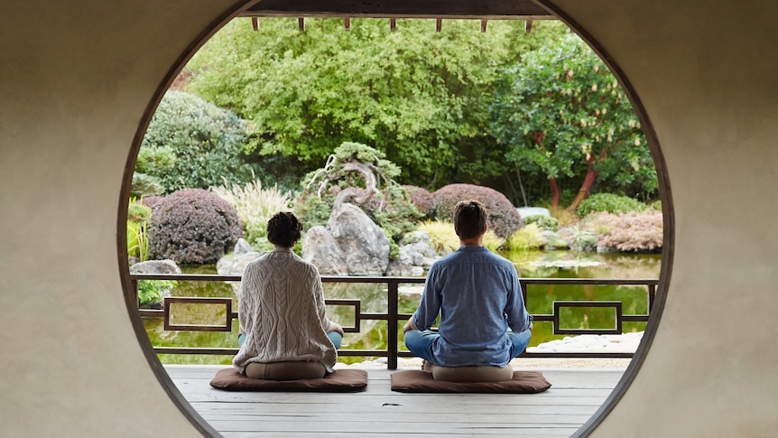 A couple meditates in a traditional Japanese building.