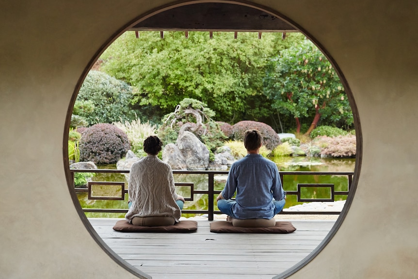 A couple meditates in a traditional Japanese building.