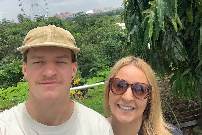 A smiling man in a cap next to a woman with sunglasses on.