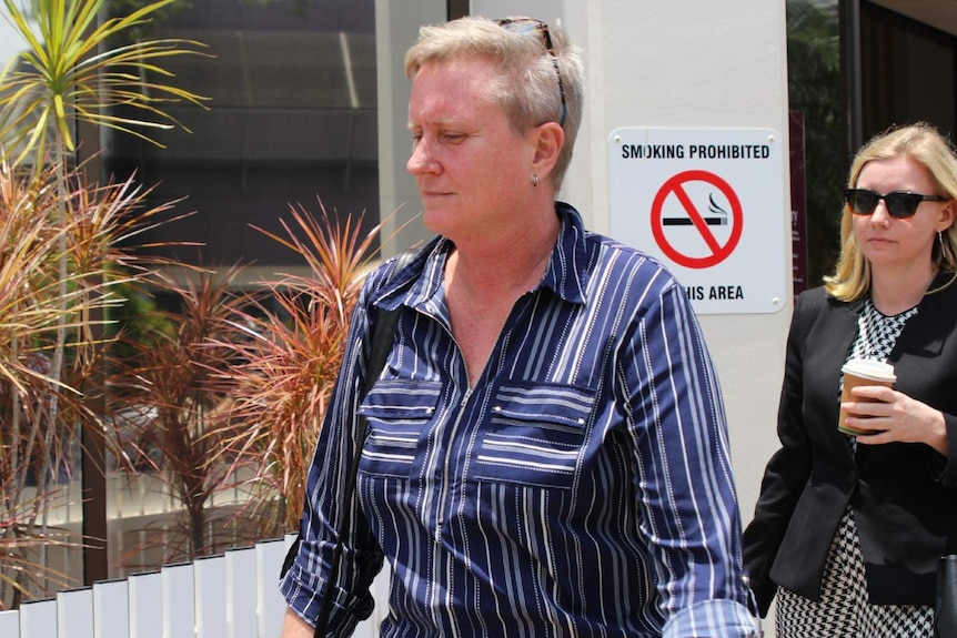 A woman wearing a collared shirt exits the Darwin Local Court.