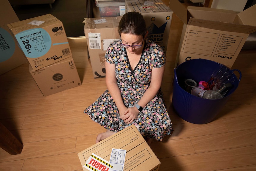 Kellee looks down at a box she is packing.