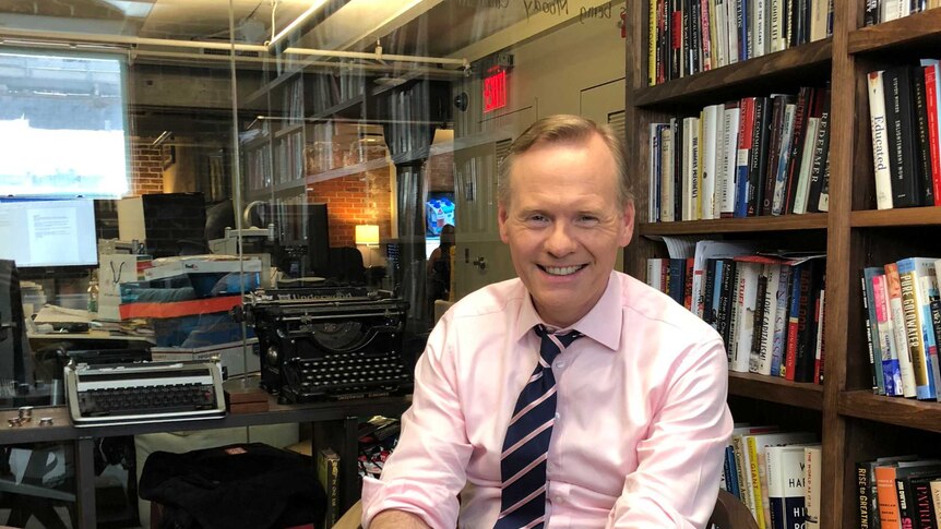 American journalist John Dickerson, a co-host of CBS This Morning. He is sitting in an office beside a bookshelf.