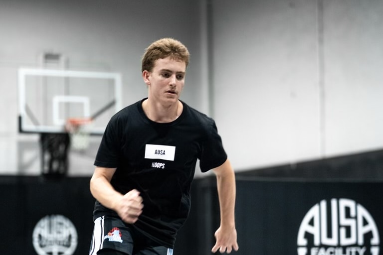 Brunette young man running with basketball bouncing in front of him