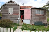 A weatherboard house with a rusted tin roof