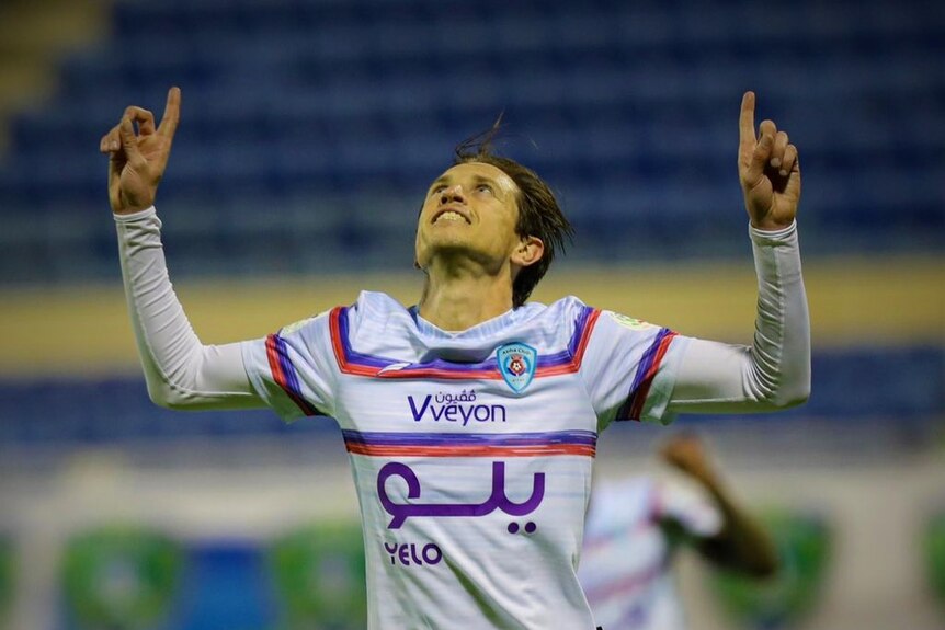 Craig Goodwin points to the sky with both hands as he celebrates a goal for Abha FC in the Saudi Pro League.