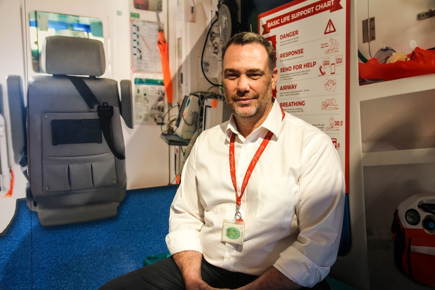 A man smiles at the camera as he sits in a child's play room