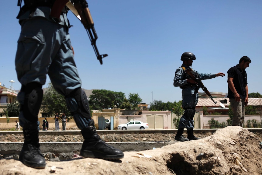 Afghan police officers stand guard near the site of an explosion in Kabul June 18, 2013.