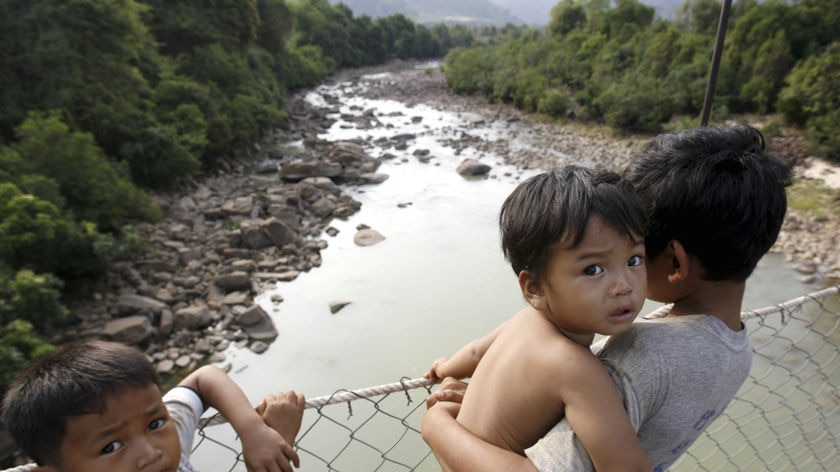 Children stand on a bridge across a river in Kamport province, Cambodia