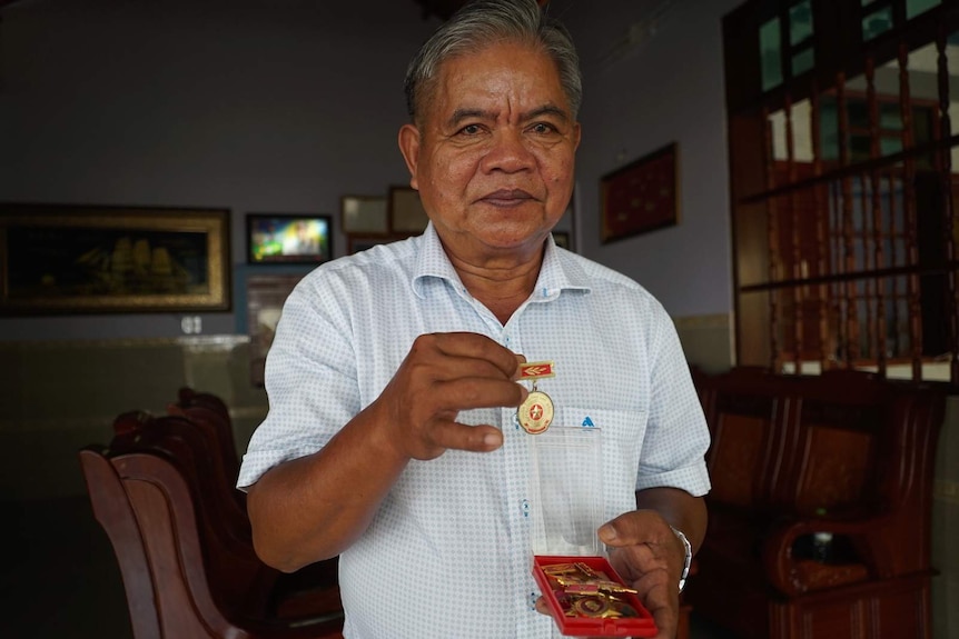 A Vietnamese war veteran shows his military and communist party medals.