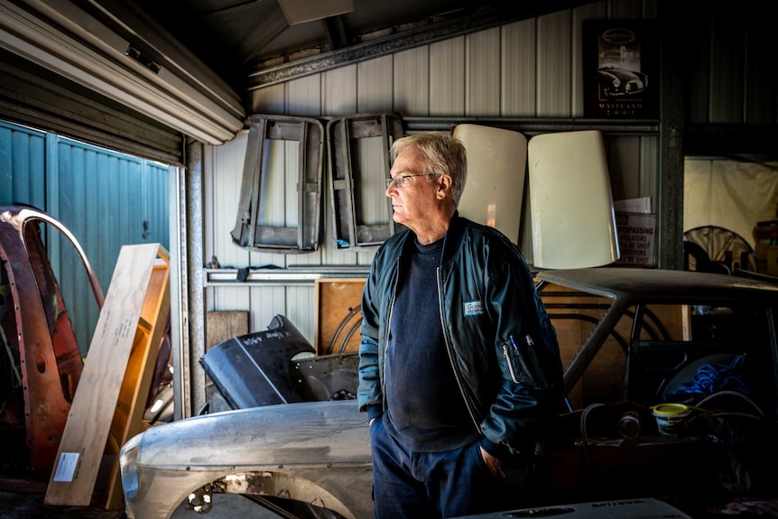 Greg Keenan stands in his garage, looking out through the door to outside.