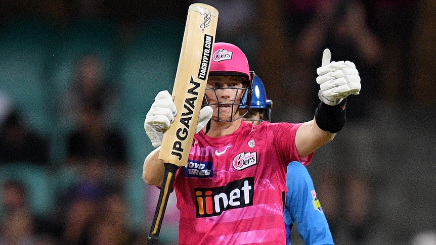 A Sydney Sixers BBL player raises his bat after reaching a half-century.