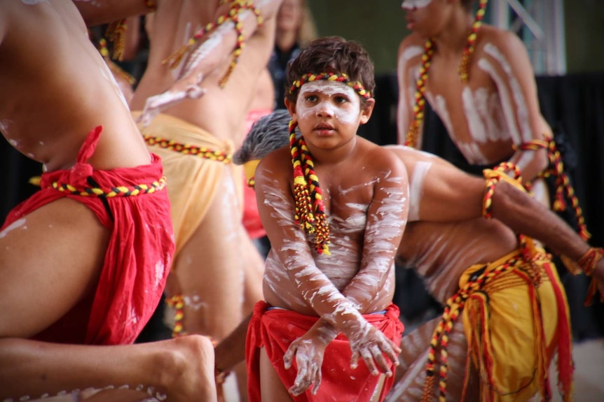 A young boy dances wearing body paint