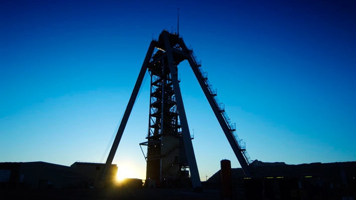 Upshot of the headframe at Newcrest Mining's gold and copper mine in silhouette against a vivid blue sky.