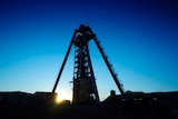 Upshot of the headframe at Newcrest Mining's gold and copper mine in silhouette against a vivid blue sky.