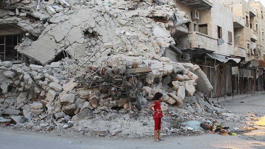 Girl stands by building damaged by Syrian forces