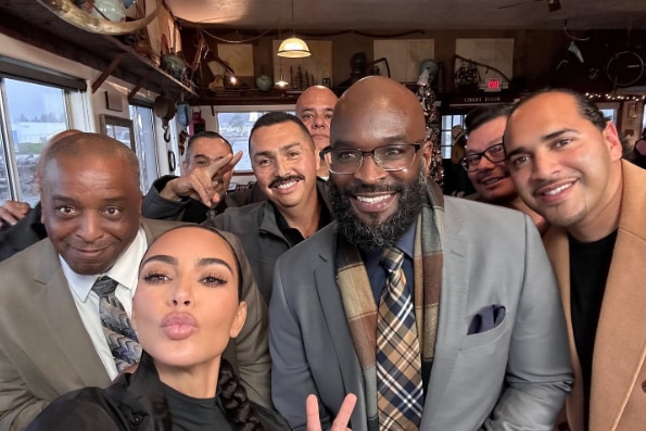 Kim Kardashian poses with a group of men in suits 