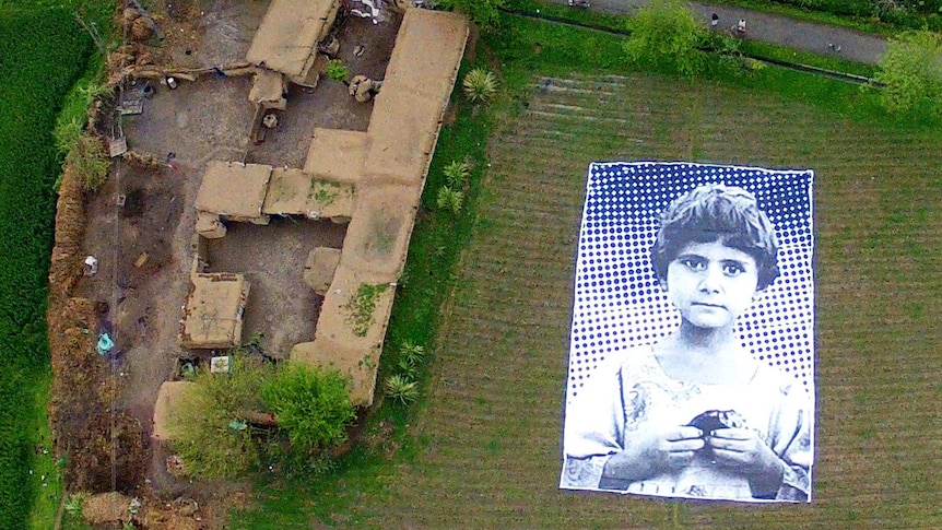 A poster bearing the image of a Pakistani girl lies in a field at an undisclosed location in Pakistan.